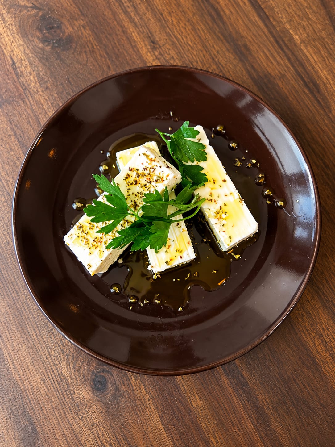 Feta mit Kräutern und Olivenöl auf dunklem Teller - POPI, Berlin-Schöneberg